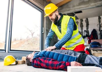 Accident of a worker at the construction site. A man performing cardiopulmonary resuscitation.
